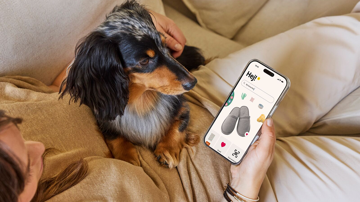 Osoba si prohlíží v mobilu aplikaci IKEA, na klíně jí sedí pes.