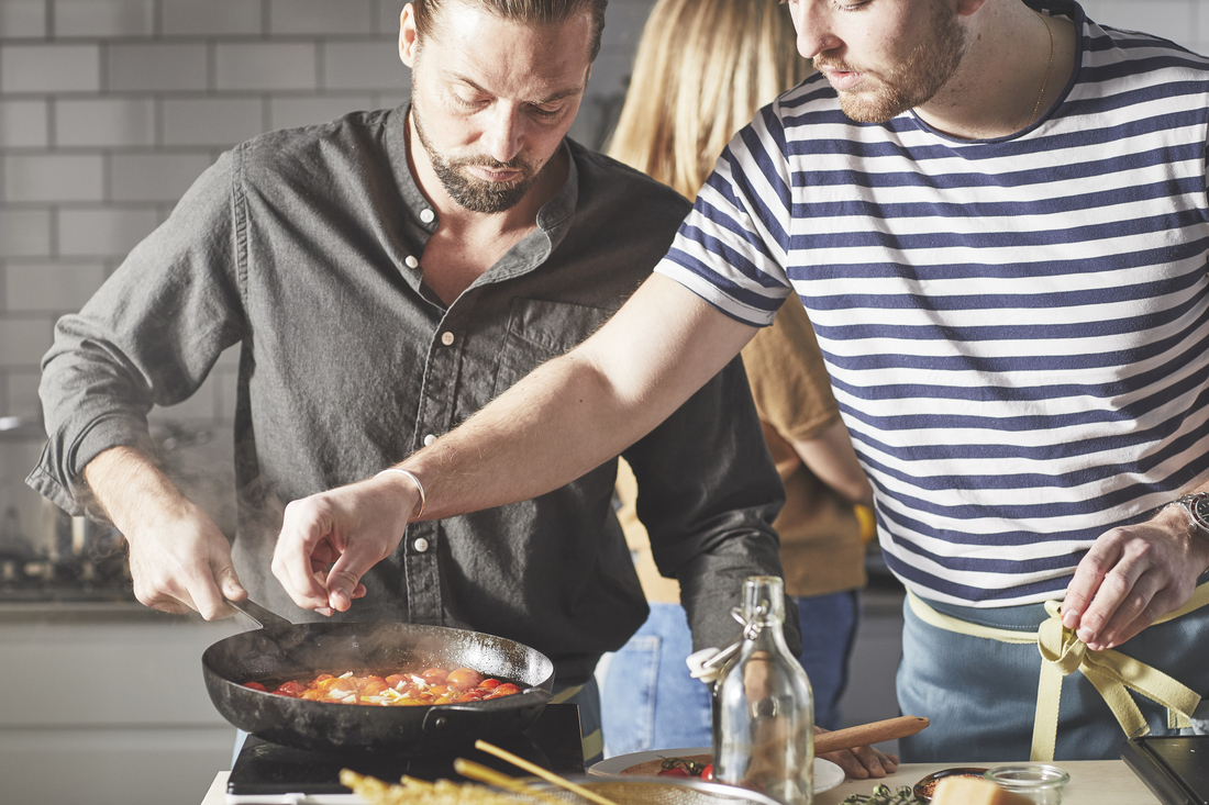 Dva muži vaří na pánvi.