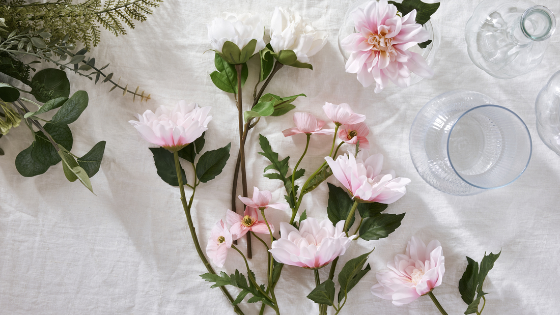 Umělé květiny SMYCKA leží na prostřeném stole.